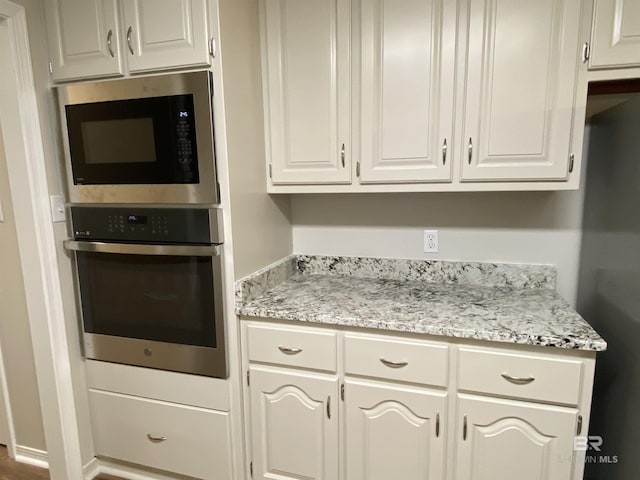 kitchen featuring white cabinetry, light stone countertops, and appliances with stainless steel finishes