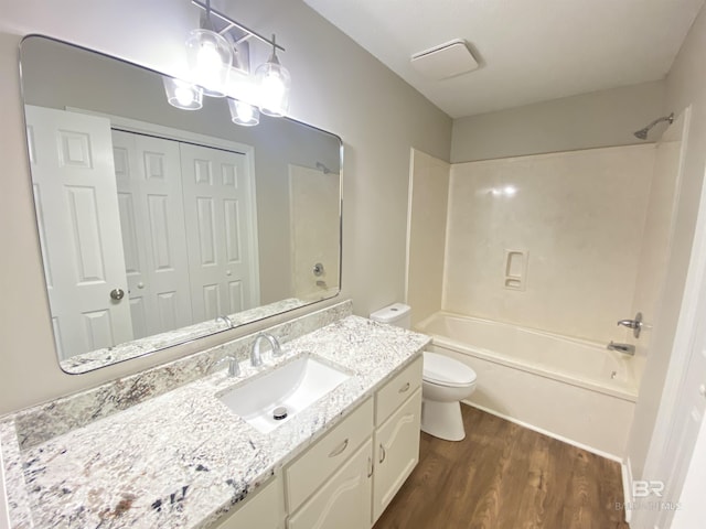 bathroom with toilet, tub / shower combination, wood finished floors, and vanity