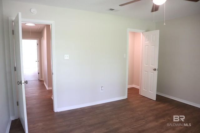 unfurnished bedroom featuring baseboards, attic access, dark wood-style floors, and visible vents