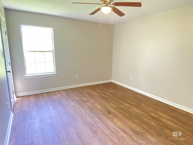 spare room with baseboards, ceiling fan, and wood finished floors