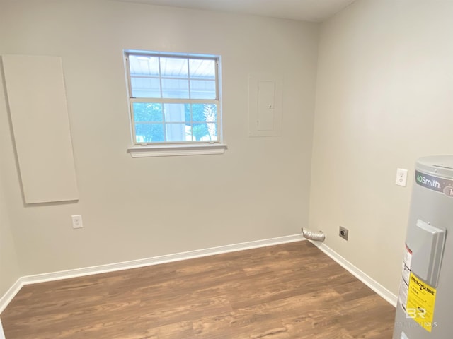 empty room with baseboards, wood finished floors, and electric water heater