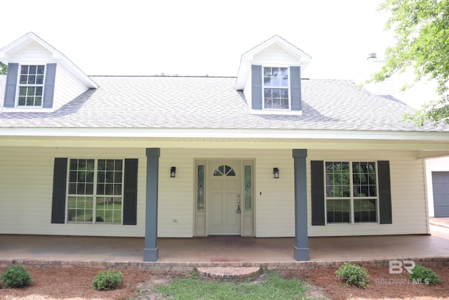 cape cod home with covered porch and a shingled roof