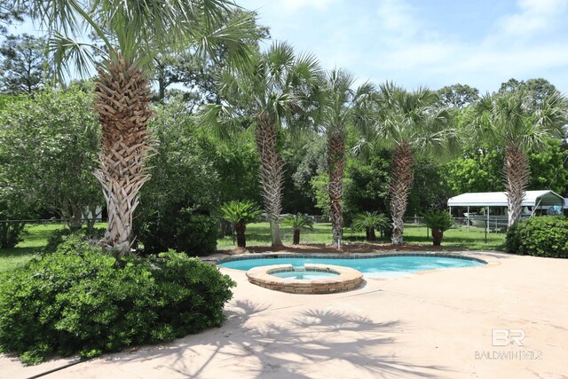 view of pool featuring a pool with connected hot tub and fence