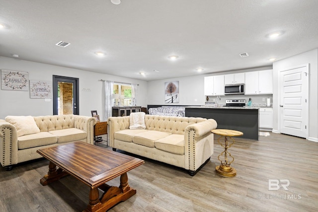 living room with a textured ceiling and light hardwood / wood-style flooring