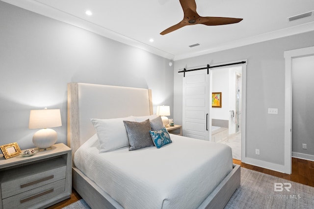 bedroom with connected bathroom, ceiling fan, a barn door, dark hardwood / wood-style floors, and ornamental molding