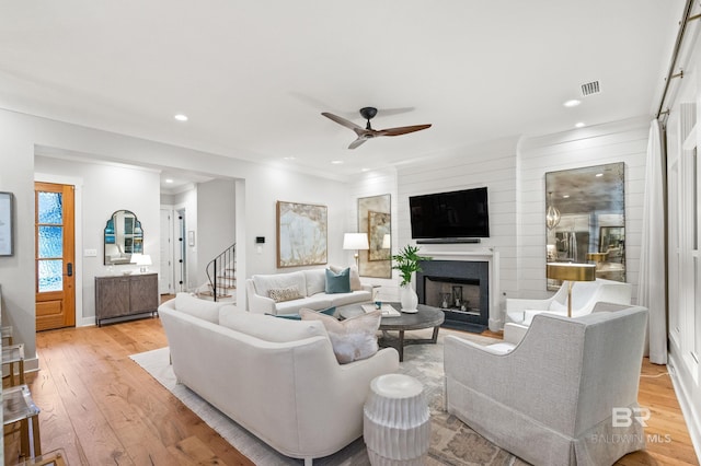 living room with ceiling fan, ornamental molding, and light wood-type flooring