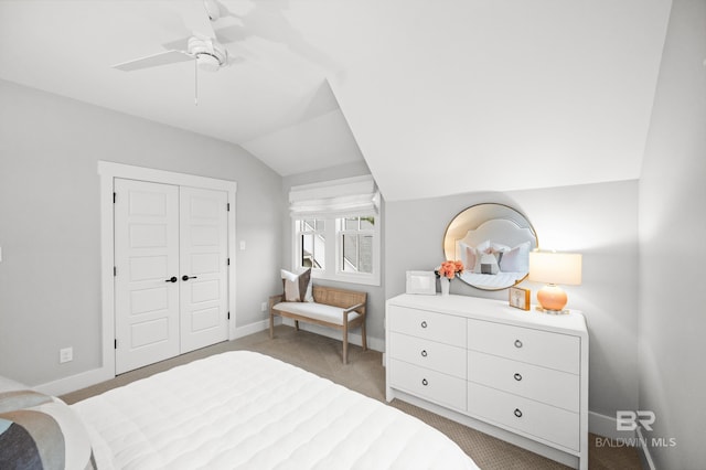 carpeted bedroom with ceiling fan, a closet, and vaulted ceiling