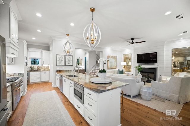 kitchen featuring white cabinets, decorative light fixtures, and a large island with sink