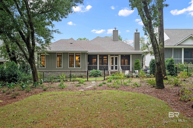 back of house with a sunroom and a lawn