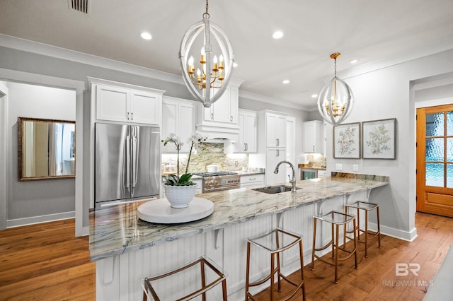 kitchen featuring sink, white cabinets, decorative light fixtures, and appliances with stainless steel finishes