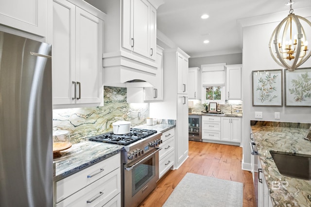 kitchen featuring wine cooler, light stone countertops, decorative light fixtures, white cabinetry, and stainless steel appliances