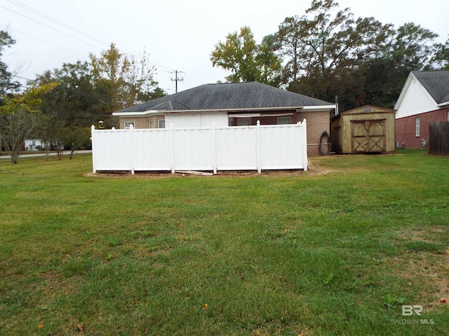 rear view of property featuring a lawn and a storage unit