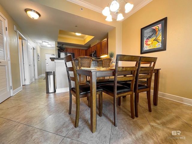 dining room featuring crown molding, a raised ceiling, baseboards, and light tile patterned floors