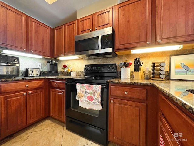 kitchen featuring backsplash, black range with electric stovetop, light tile patterned floors, stainless steel microwave, and dark stone counters