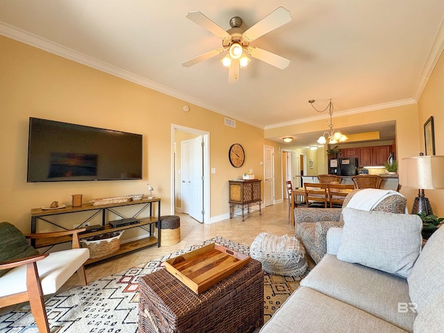 living room featuring crown molding, light tile patterned flooring, ceiling fan with notable chandelier, baseboards, and visible vents