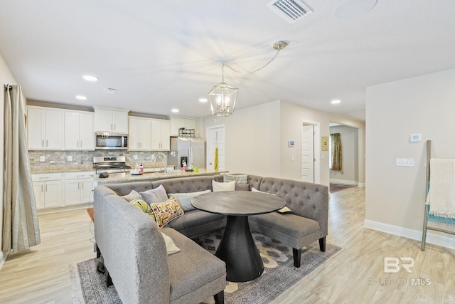 dining area with a notable chandelier, light wood-type flooring, and sink