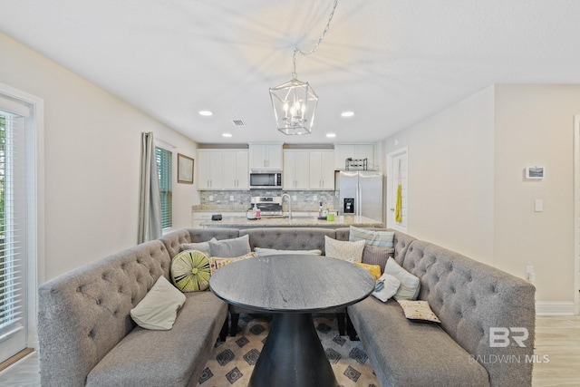 living room featuring an inviting chandelier, light wood-type flooring, and sink