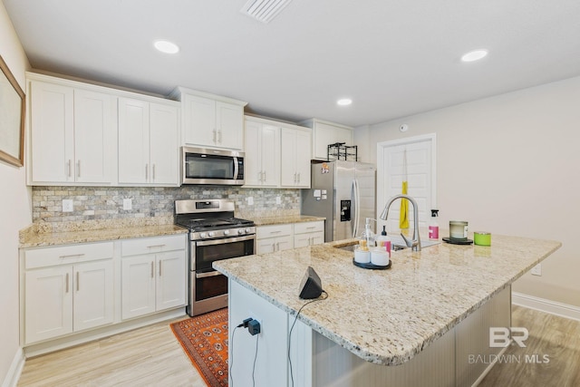 kitchen with stainless steel appliances, light hardwood / wood-style floors, and white cabinetry