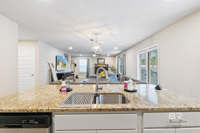 kitchen featuring ceiling fan with notable chandelier, an island with sink, and sink