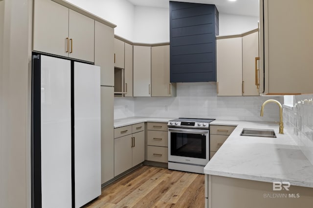 kitchen featuring stainless steel electric stove, freestanding refrigerator, a sink, ventilation hood, and light wood-type flooring