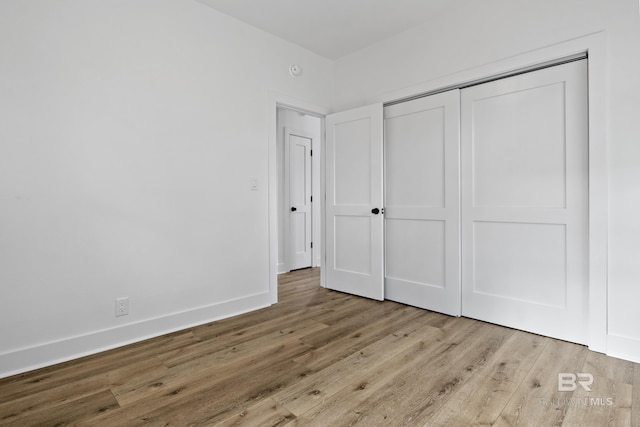 unfurnished bedroom with light wood-style flooring, baseboards, and a closet