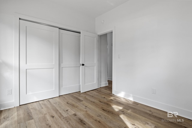 unfurnished bedroom with light wood finished floors, a closet, and baseboards