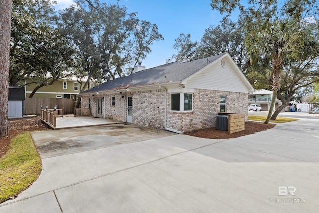 exterior space featuring a chimney, fence, and brick siding