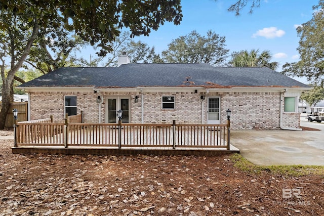 back of house featuring french doors, a patio, a chimney, a wooden deck, and brick siding