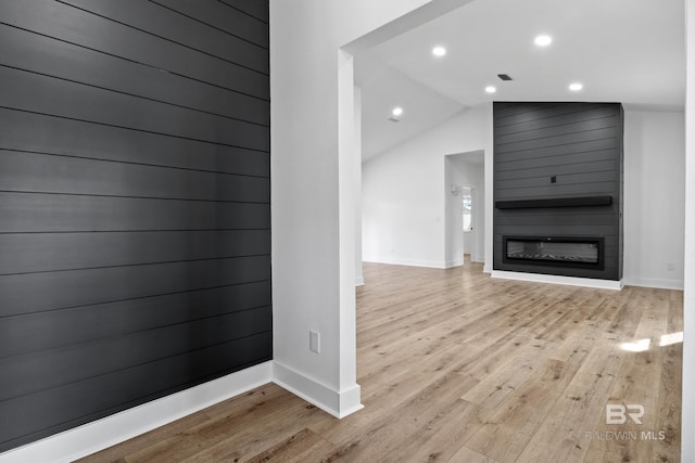 unfurnished living room featuring recessed lighting, a large fireplace, vaulted ceiling, and light wood finished floors