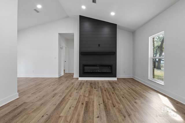 unfurnished living room featuring a large fireplace, light wood-style flooring, plenty of natural light, and visible vents