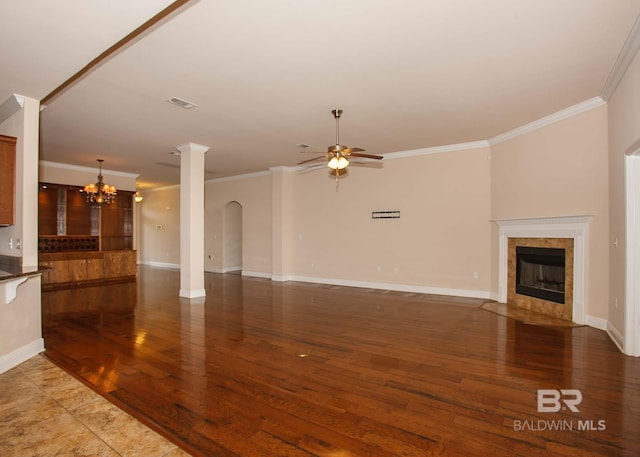 unfurnished living room featuring ornamental molding, dark hardwood / wood-style flooring, ceiling fan with notable chandelier, and a fireplace