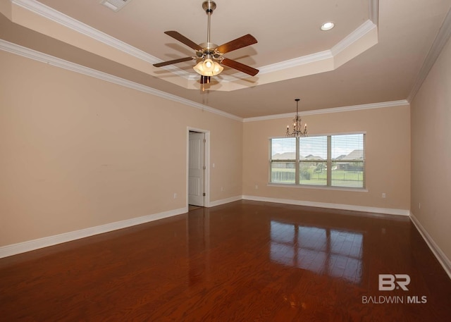 empty room with a tray ceiling, ceiling fan with notable chandelier, ornamental molding, and dark hardwood / wood-style floors