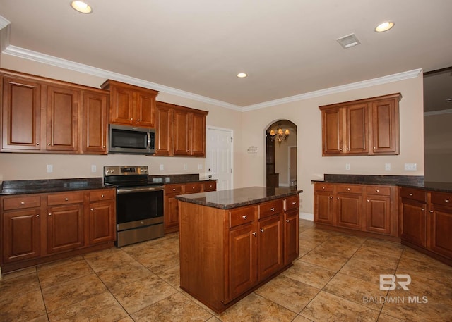 kitchen with crown molding, a kitchen island, dark stone counters, and appliances with stainless steel finishes