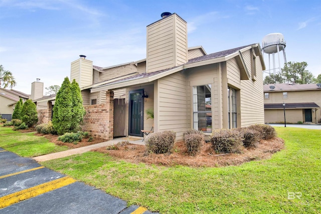 view of front of home with brick siding, a chimney, and a front yard