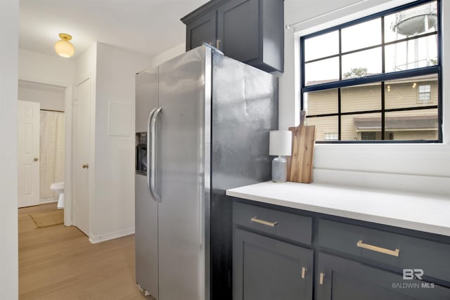 kitchen featuring light countertops, gray cabinets, stainless steel fridge with ice dispenser, and light wood-style floors