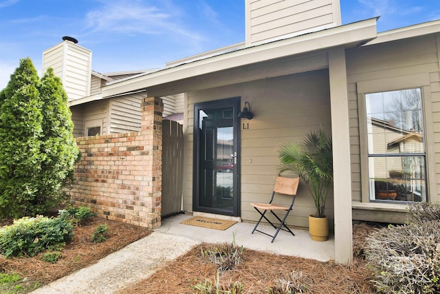 doorway to property with brick siding and a chimney