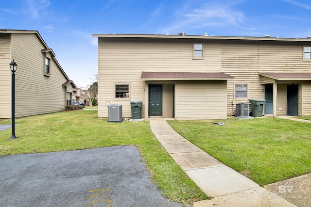 back of property featuring cooling unit and a lawn