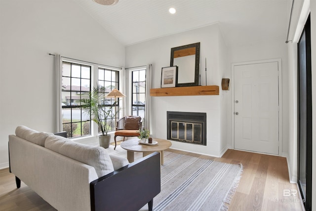 living room with baseboards, vaulted ceiling, recessed lighting, wood finished floors, and a glass covered fireplace