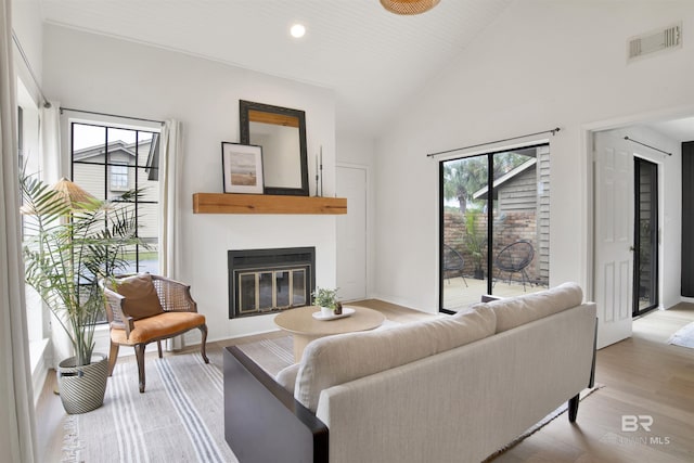 living room with a wealth of natural light, visible vents, wood finished floors, and a glass covered fireplace