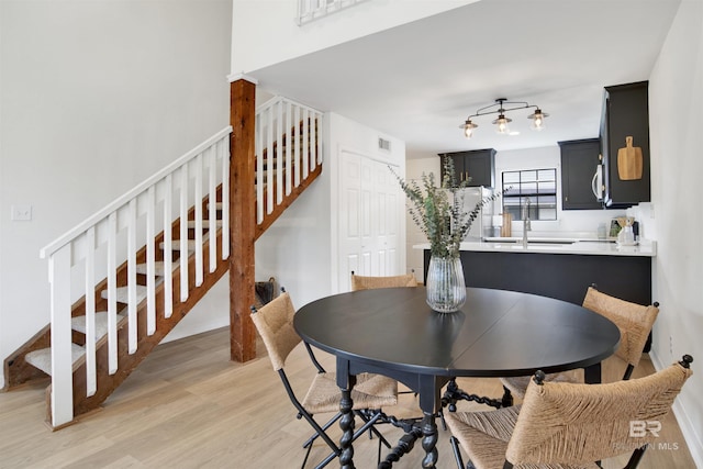 dining room with light wood-type flooring, visible vents, and stairs