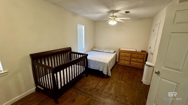 bedroom featuring ceiling fan, dark wood-type flooring, and a textured ceiling