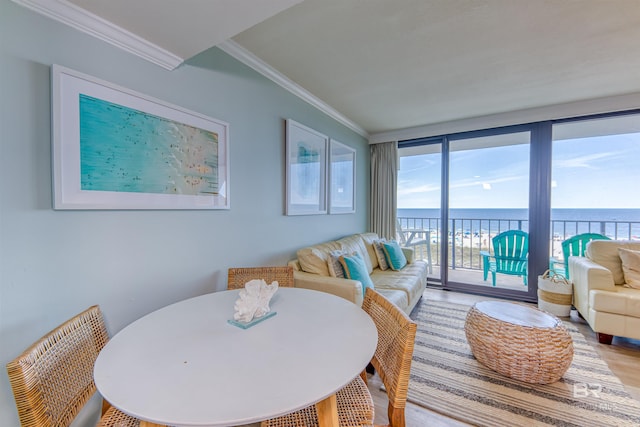 dining area with expansive windows, ornamental molding, a water view, and hardwood / wood-style floors