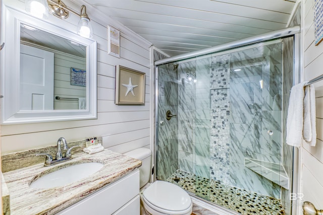 bathroom with vanity, wooden walls, a shower with door, and toilet