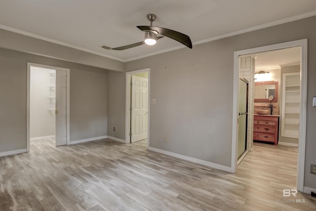 unfurnished bedroom with crown molding, a spacious closet, light hardwood / wood-style floors, and a closet