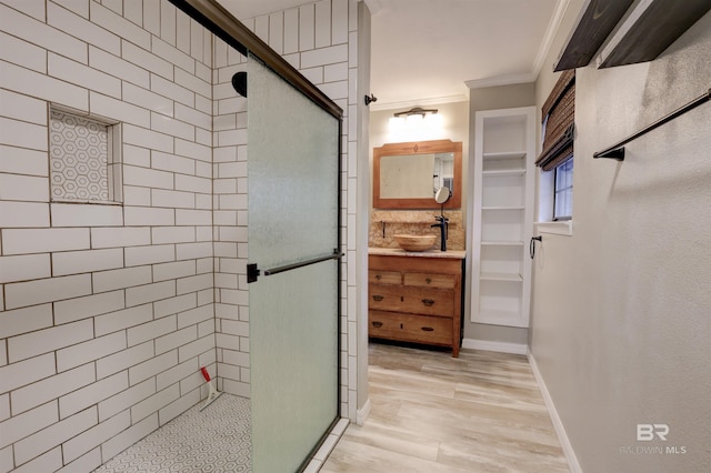 bathroom with ornamental molding, hardwood / wood-style floors, vanity, and a shower with shower door