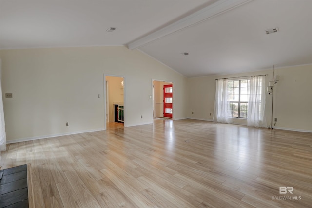 spare room featuring lofted ceiling with beams and light wood-type flooring