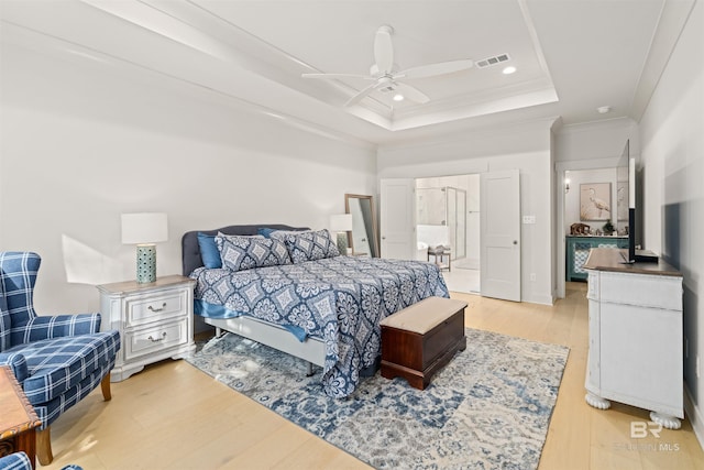 bedroom featuring light wood-type flooring, a tray ceiling, ceiling fan, and crown molding