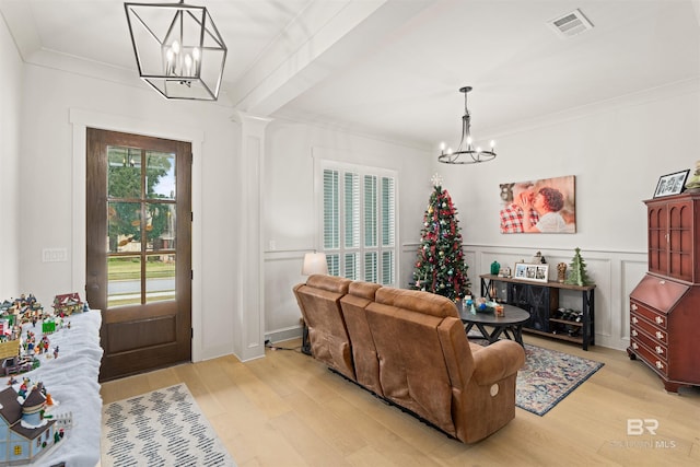 living room featuring light wood-type flooring, an inviting chandelier, and ornamental molding