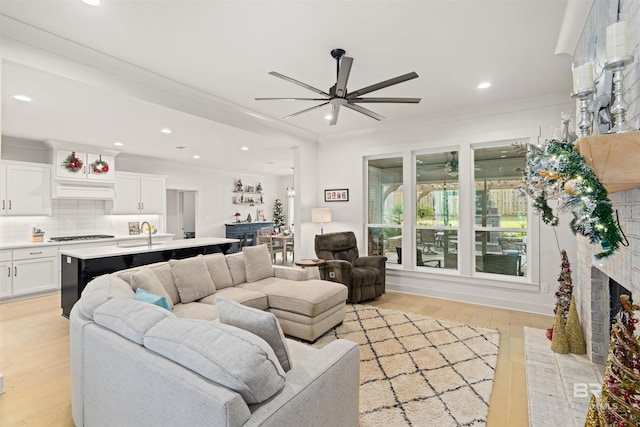 living room with crown molding, sink, and light hardwood / wood-style flooring