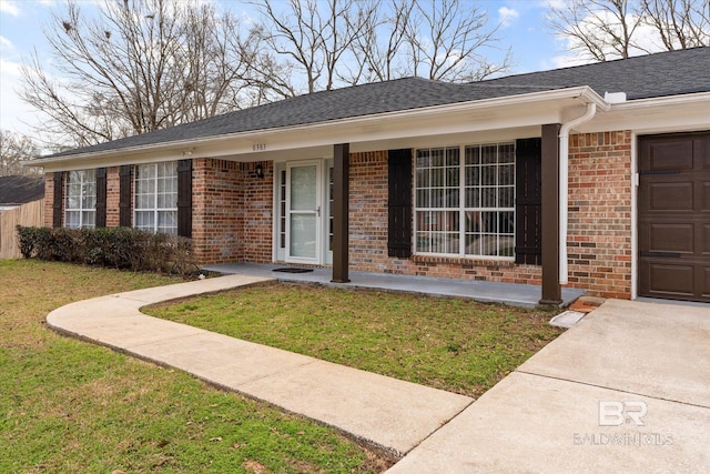 view of front facade featuring brick siding, a front lawn, and roof with shingles